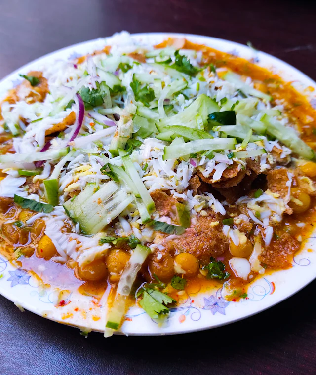 Plate of home-cooked chole topped with fresh onion, coriander and sev